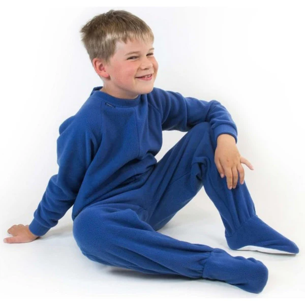 Smiling boy sits wearing all in one zip up fleece pjamas which cover the feet